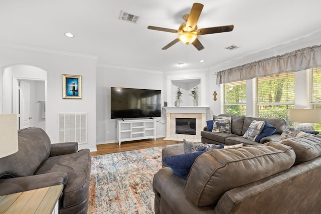 living room with hardwood / wood-style flooring, ceiling fan, ornamental molding, and a tile fireplace