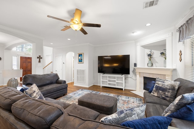 living room with hardwood / wood-style floors, a fireplace, ceiling fan, and crown molding