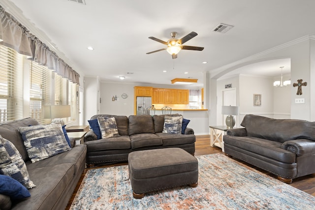 living room with crown molding, ceiling fan with notable chandelier, and dark hardwood / wood-style floors