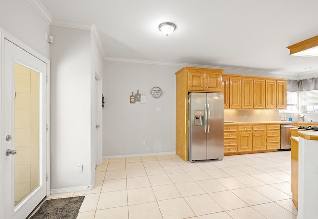 kitchen featuring appliances with stainless steel finishes, light brown cabinets, light tile patterned floors, and ornamental molding