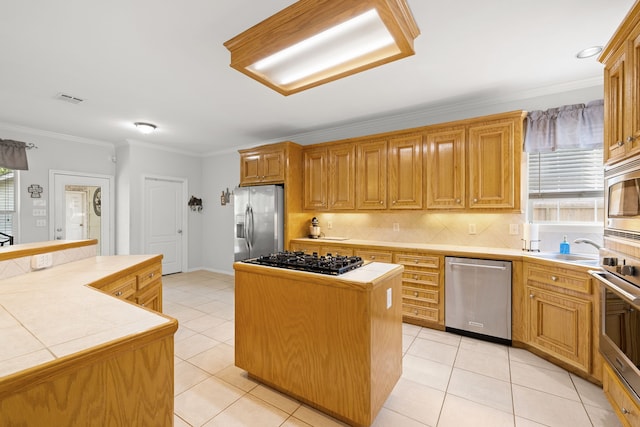 kitchen with appliances with stainless steel finishes, backsplash, tile countertops, and a kitchen island