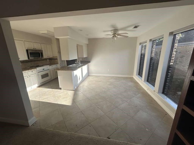 12 Windsor Ct, Lufkin, TX 75901 - kitchen with stainless steel microwave, baseboards, ceiling fan, a peninsula, and white cabinetry