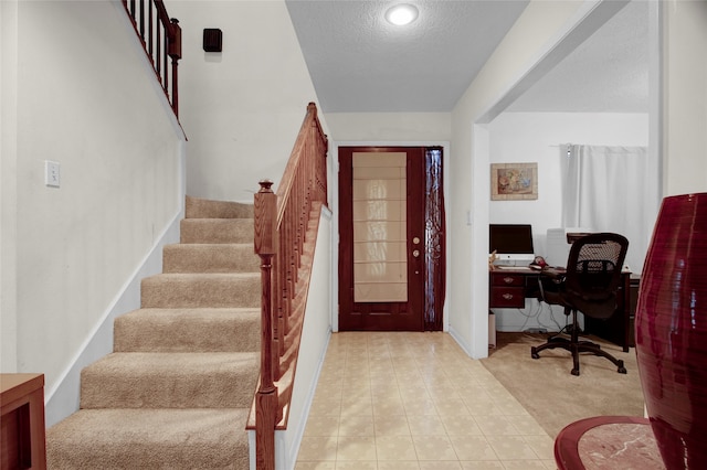 foyer entrance featuring light carpet and a textured ceiling