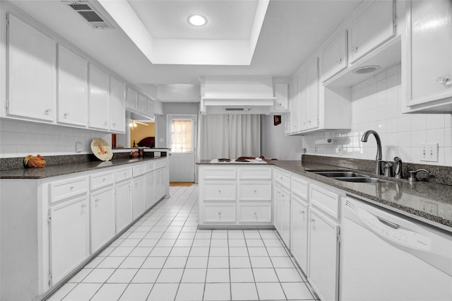 kitchen featuring a tray ceiling, sink, light tile patterned floors, dishwasher, and white cabinetry