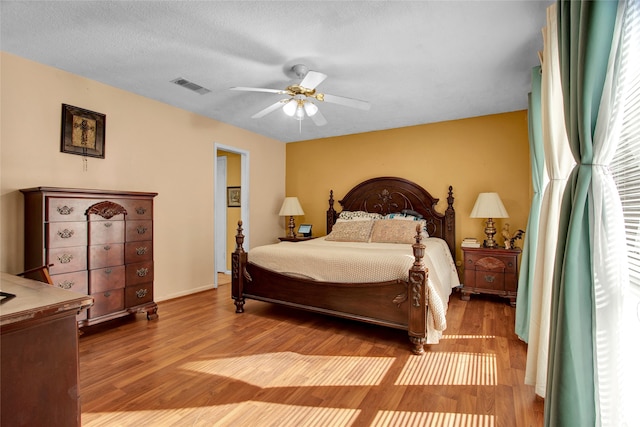 bedroom featuring hardwood / wood-style floors, ceiling fan, and a textured ceiling