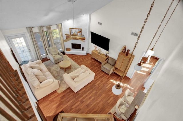 living room with a large fireplace, hardwood / wood-style flooring, and high vaulted ceiling