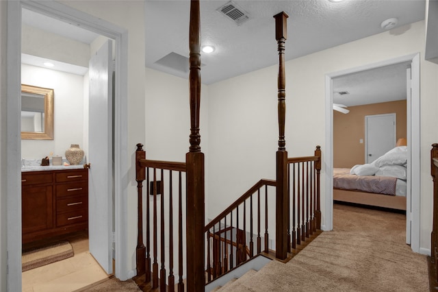 hall with a textured ceiling and light carpet