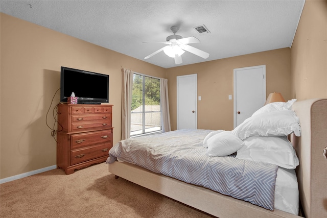 carpeted bedroom with ceiling fan and a textured ceiling