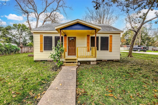 bungalow with roof with shingles, a front yard, and fence