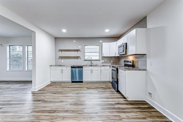 kitchen with dark stone counters, sink, light hardwood / wood-style flooring, white cabinetry, and stainless steel appliances