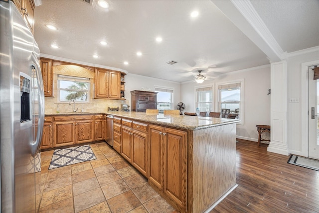 kitchen featuring plenty of natural light, kitchen peninsula, crown molding, and appliances with stainless steel finishes