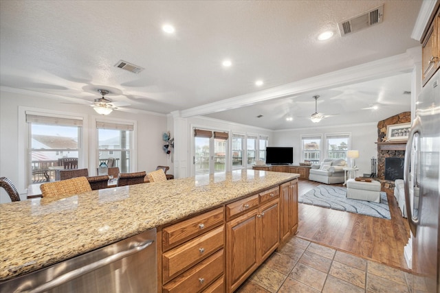 kitchen with light wood-type flooring, stainless steel appliances, ornamental molding, and a breakfast bar area