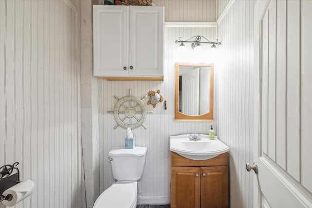 bathroom with wood walls, vanity, and toilet