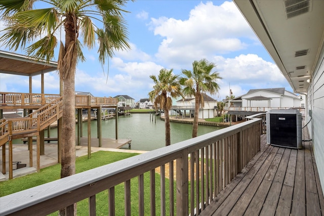 wooden deck with a lawn, a water view, and a dock