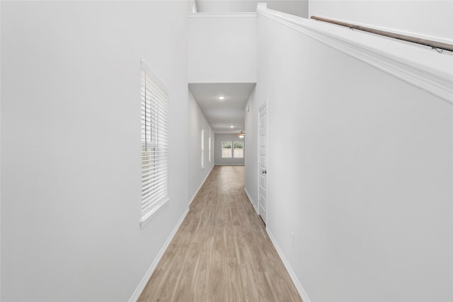 hallway with light hardwood / wood-style floors and a towering ceiling