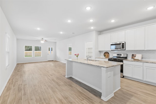 kitchen featuring white cabinetry, sink, light hardwood / wood-style flooring, a center island with sink, and appliances with stainless steel finishes