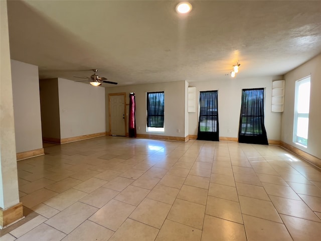 tiled empty room with ceiling fan and a textured ceiling