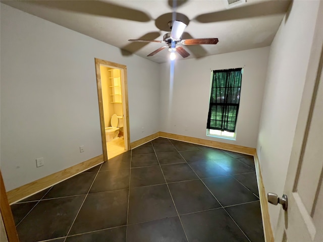 empty room with dark tile patterned floors and ceiling fan