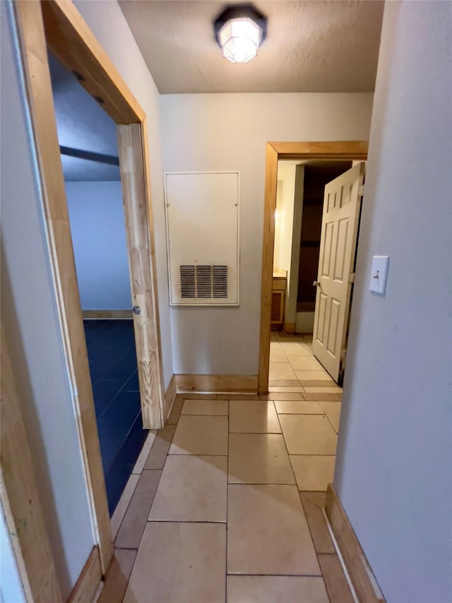 hallway featuring light tile patterned floors and a textured ceiling