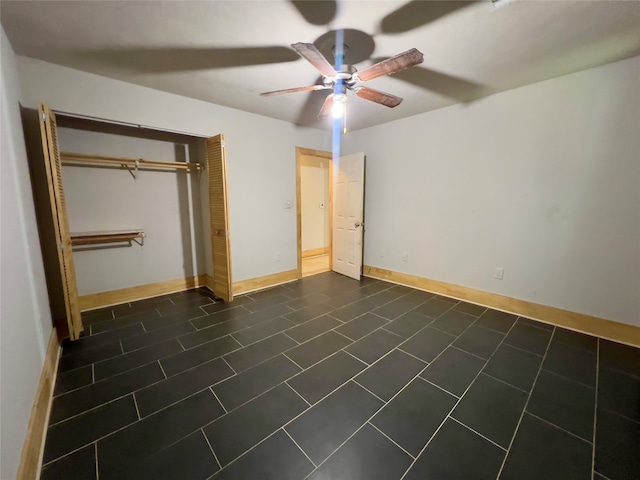 unfurnished bedroom with ceiling fan, a closet, and dark tile patterned flooring