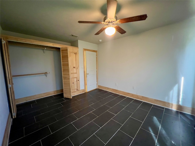 unfurnished bedroom featuring dark tile patterned flooring, ceiling fan, and a closet