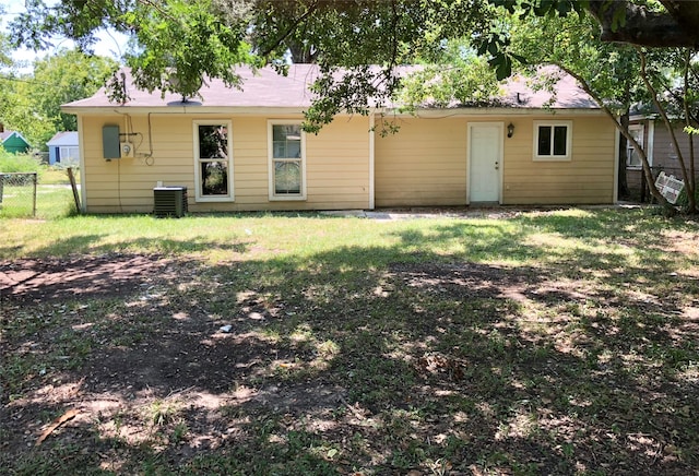 rear view of house featuring central AC unit and a lawn