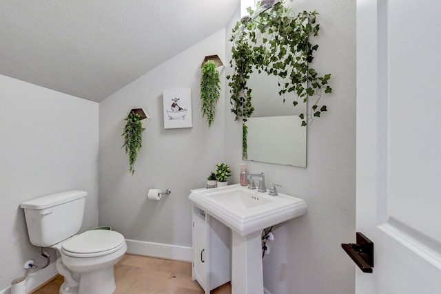 bathroom with a textured ceiling, toilet, lofted ceiling, and sink