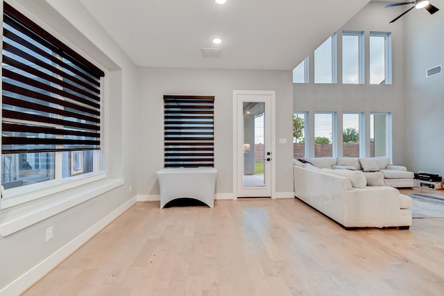 living room with light wood-type flooring, ceiling fan, and a healthy amount of sunlight