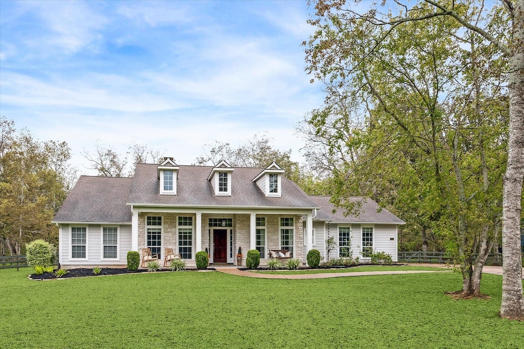 cape cod-style house with a front yard and covered porch