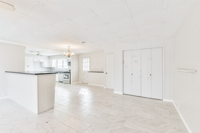 unfurnished living room with a paneled ceiling and ceiling fan with notable chandelier