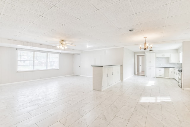 unfurnished living room featuring a drop ceiling and ceiling fan with notable chandelier