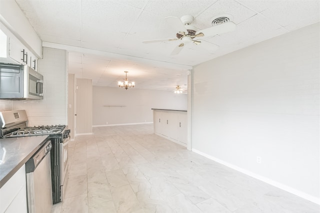 kitchen featuring stainless steel appliances, backsplash, decorative light fixtures, white cabinets, and ceiling fan with notable chandelier