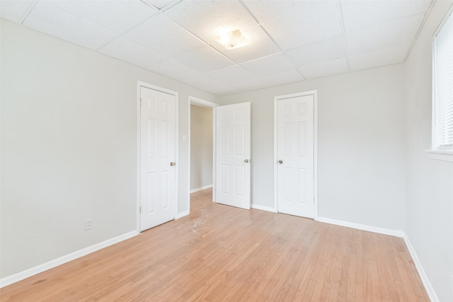 unfurnished bedroom featuring a paneled ceiling and light wood-type flooring