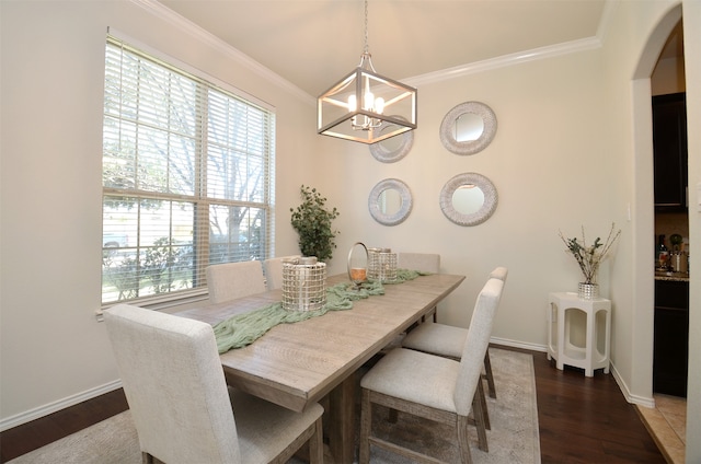 dining space with dark hardwood / wood-style flooring, crown molding, and an inviting chandelier