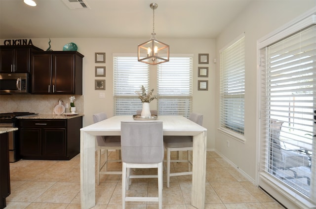 dining room with plenty of natural light, light tile patterned flooring, and a notable chandelier