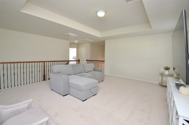 living room with a raised ceiling and light colored carpet