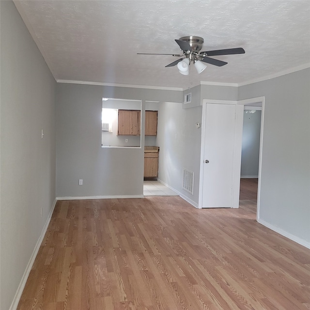 empty room with ceiling fan, light hardwood / wood-style flooring, crown molding, and a textured ceiling