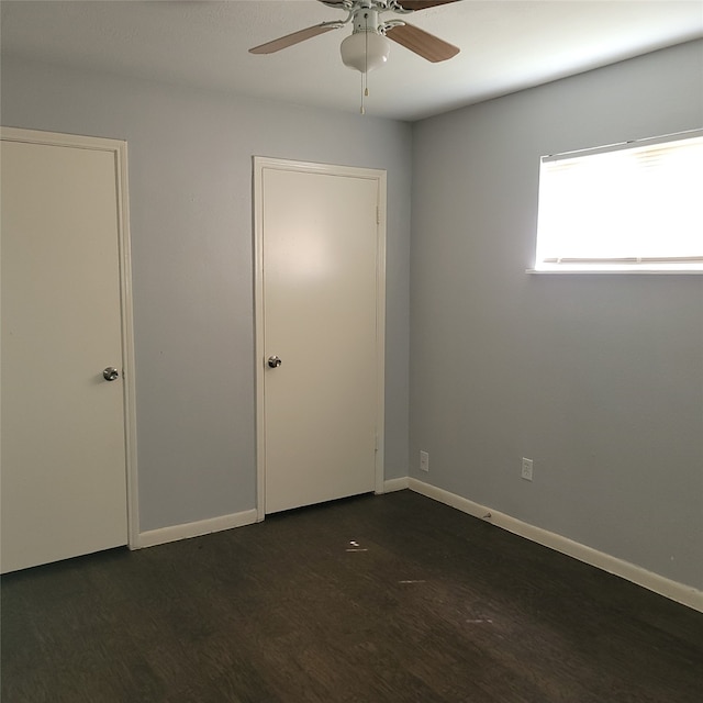 empty room with dark hardwood / wood-style flooring and ceiling fan