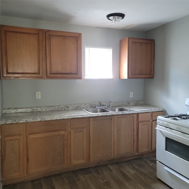 kitchen with white gas range, dark wood-type flooring, and sink