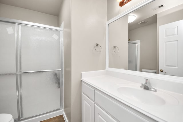 bathroom featuring vanity, an enclosed shower, and toilet