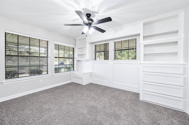 carpeted spare room featuring built in shelves and ceiling fan