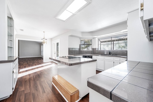 kitchen featuring dark hardwood / wood-style flooring, pendant lighting, a breakfast bar area, white cabinets, and black appliances