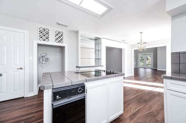 kitchen featuring black electric cooktop, dark wood-type flooring, an inviting chandelier, white cabinets, and hanging light fixtures