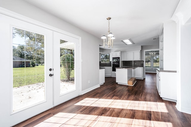 kitchen featuring white cabinetry, dark wood-type flooring, an inviting chandelier, decorative light fixtures, and decorative backsplash