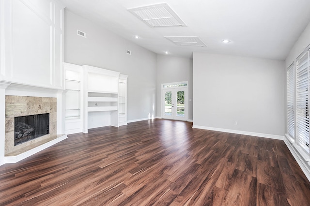 unfurnished living room featuring a tile fireplace, french doors, high vaulted ceiling, and dark wood-type flooring