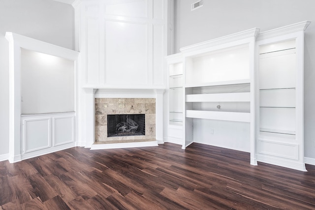 unfurnished living room with built in features, dark wood-type flooring, and a tile fireplace