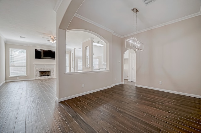 interior space featuring a fireplace, dark hardwood / wood-style flooring, ceiling fan with notable chandelier, and crown molding