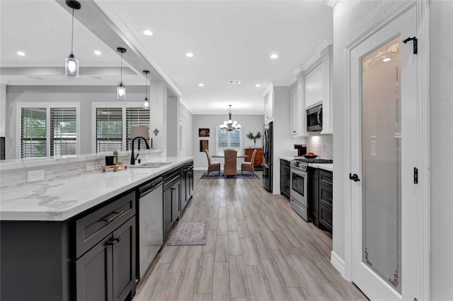 kitchen featuring pendant lighting, sink, light hardwood / wood-style flooring, decorative backsplash, and appliances with stainless steel finishes