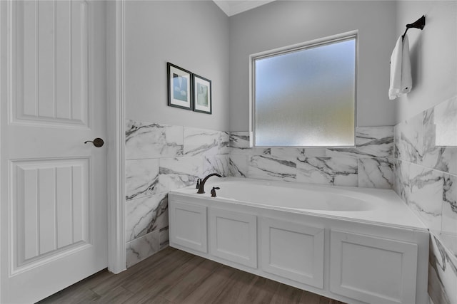 bathroom with a bathing tub, hardwood / wood-style floors, and tile walls