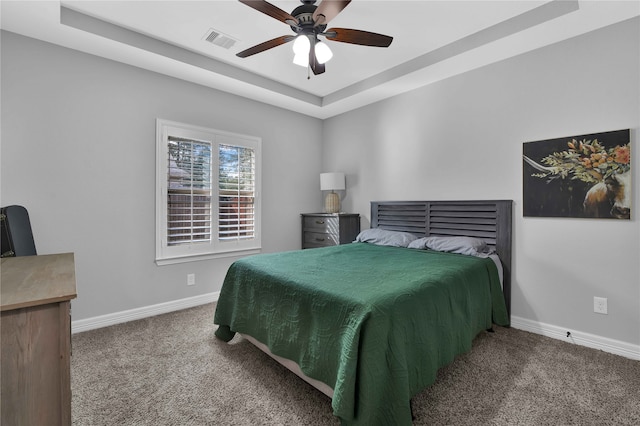 carpeted bedroom featuring a raised ceiling and ceiling fan